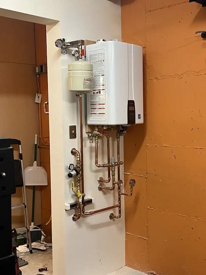 Plumbing technician inspecting water heater connections in Logan